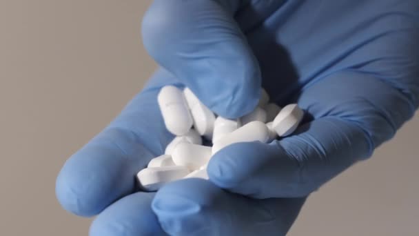 Primer plano de una mano con guantes de goma sosteniendo pastillas blancas. — Vídeo de stock