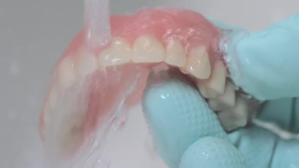 Крупним планом знімок, що показує очищення зубів протеза під проточною водою . — стокове відео