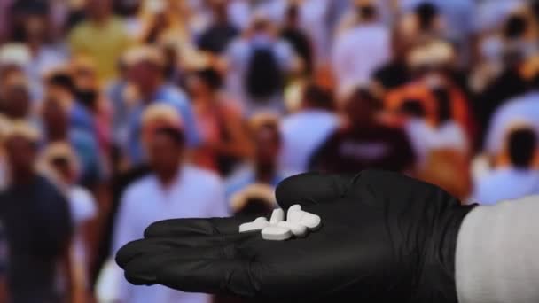En hand i svarta latexhandskar med vita piller. — Stockvideo