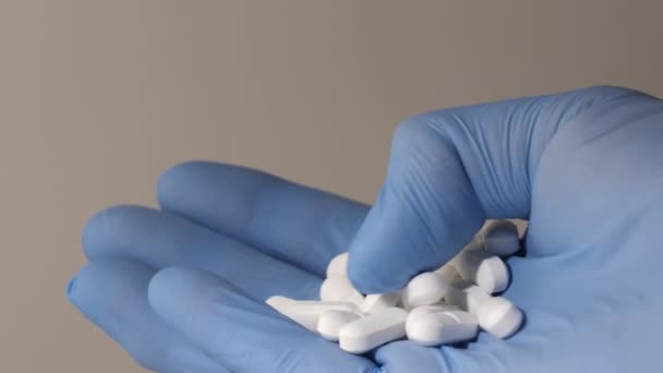 Närbild skott av en hand i latexhandskar som håller vita piller. — Stockvideo