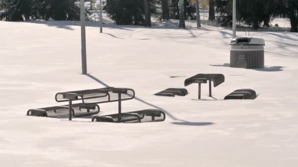 Piękne ujęcie ławek i stołów w zaśnieżonym parku. — Wideo stockowe