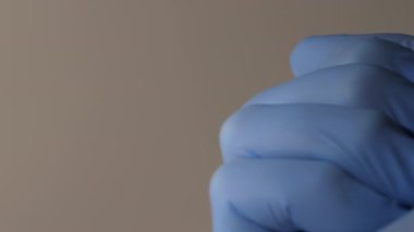 Elinde haplar tutan lateks eldivenli bir elin yakın plan fotoğrafı..
