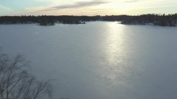 Pretty drone shot of the frozen sea between the small islands during sunset. — Stock Video