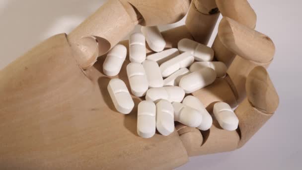 Closeup shot of white pills on a wooden hand. — Stock Video