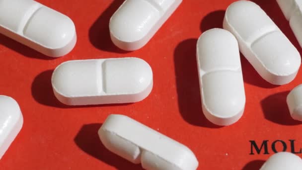 Closeup shot of white tablets on red background with black text. — Video Stock