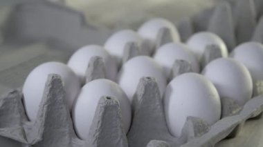 Büyük taze beyaz yumurtalar tepsiye konuyor. Yakın plan.