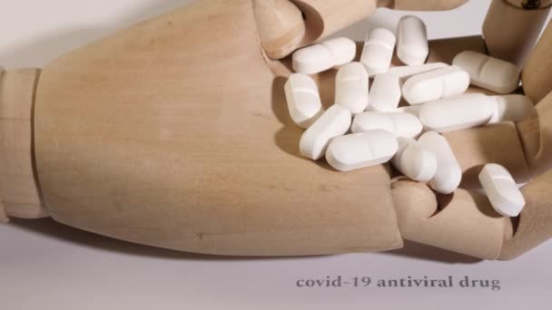 Primer plano de píldoras blancas en una mano maniquí de madera. — Vídeos de Stock