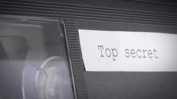 Üzerinde "çok gizli" yazan bir tabelanın olduğu çalışan bir video kasetinin yakın çekimi.. — Stok video