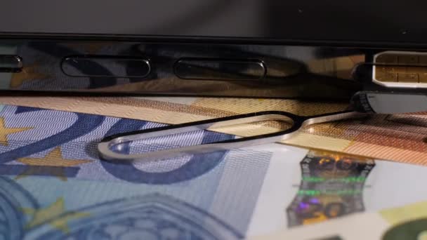 Primer plano de la moneda y una tarjeta SIM cerca de un teléfono. Smartphone negro. — Vídeos de Stock