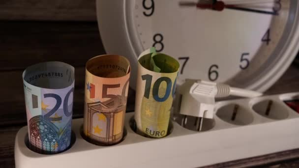Close-up shot van geld en een stopcontact met een klok achter hen. — Stockvideo