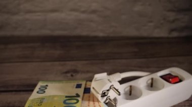Elektrik prizine yığılmış para yüksek elektrik fiyatları konseptini gösteriyor..