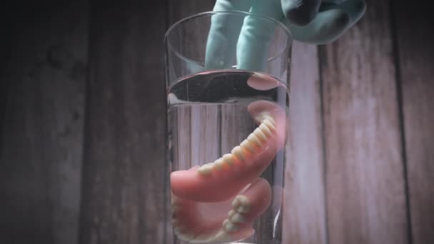 Primo piano colpo di togliere i denti protesi da un bicchiere d'acqua. — Video Stock