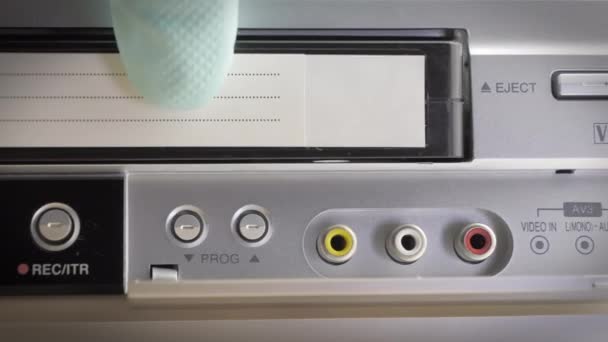 Close-up shot van een vintage vhs cassette die in een cassette speler wordt geplaatst. — Stockvideo