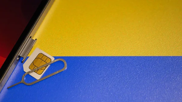 Ukrayna bayrağının yakın çekimi ve sim kartlı bir akıllı telefon. Metin uzayı. 