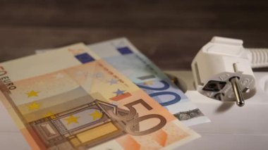 Yüksek enerji fiyatları kavramını gösteren bir sokete para koymak.