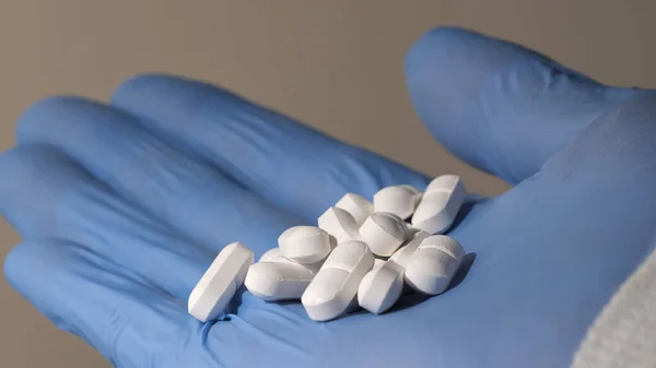 Elinde haplar tutan lateks eldivenli bir elin yakından çekimi. İlaç endüstrisi.. 
