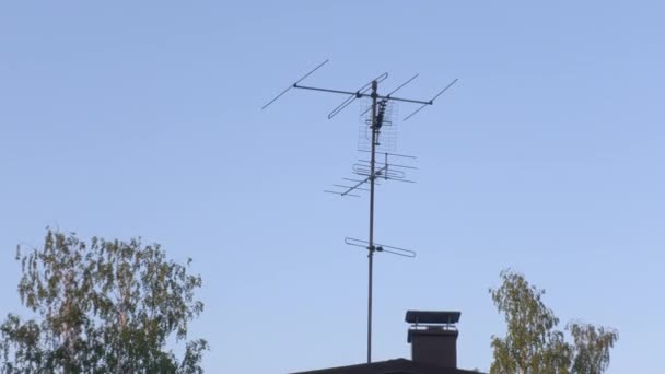 Gyönyörű kép az antennákról a tetőn kék égbolttal és fákkal a háttérben.. — Stock videók