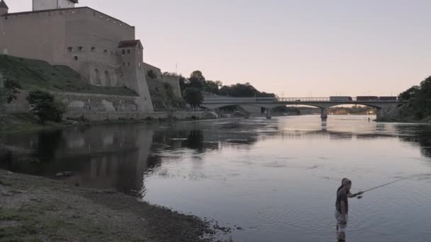 Dos hombres pescando en el río de la frontera en Narva Estonia. — Vídeos de Stock