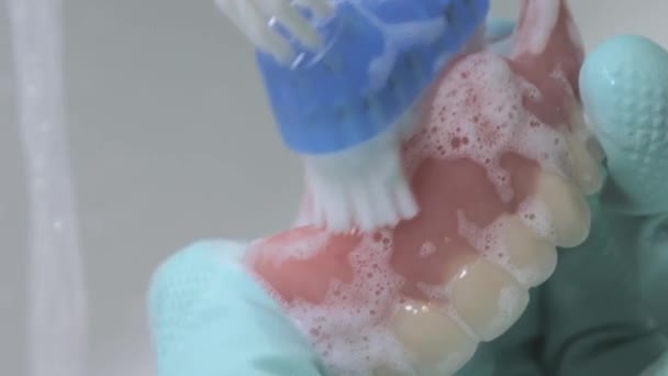Крупним планом знімок чищення зубів протеза за допомогою пензлика . — стокове відео