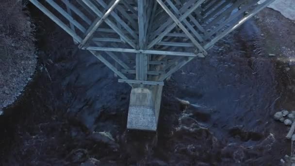 Ειδυλλιακή εναέρια λήψη ενός ποταμού με μια ξύλινη γέφυρα που διασχίζει αυτό. — Αρχείο Βίντεο