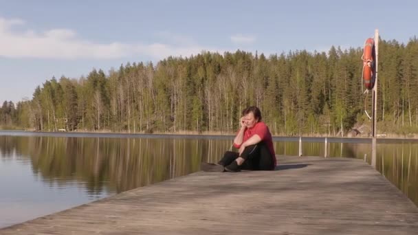 Pretty shot of a lady talking on her phone on a floating swimming bridge. — Video