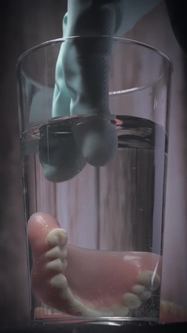Lähikuva Laukaus Poistamalla Proteesin Hampaat Lasillisesta Vettä Käyttäen Kumihansikas Asianmukaisen — kuvapankkivideo