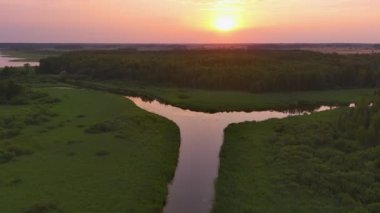 Estonya 'daki Vohandu nehrinin hayali görüntüsü. Arka planda muhteşem bir günbatımı. Güzel Estonya doğası ve manzarası. Drone yavaşça yukarı ve geri hareket ediyor. Jeoloji görüntüsü.