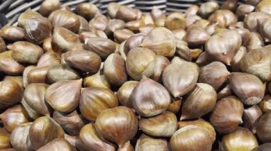 Mağazadaki yenilebilir kestanelerin yakın çekimi. Yiyecekler. Koyu ve açık kahverengi. Kamera yavaşça dönüyor.