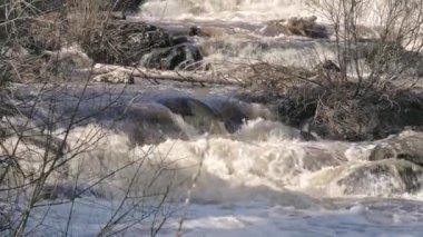 Beautiful shot of a rapid river flowing between rocks. Awesome nordic nature during spring. Geology shot with the camera slightly tilting upwards. Selective focus.