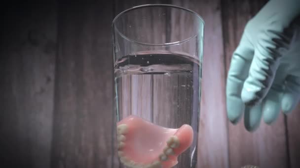 Крупный План Опускания Протезных Зубов Стакан Воды Помощью Резиновой Перчатки — стоковое видео