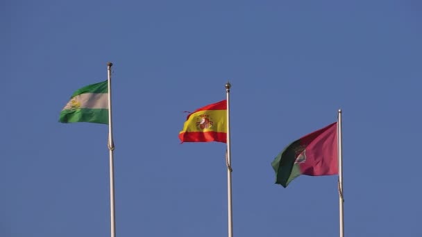西班牙 葡萄牙和安达卢西亚的国旗升起在白旗杆上 慢镜头 背景是蓝天 阳光灿烂的日子 在风中摇曳 — 图库视频影像
