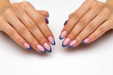 Beyaz arka planda uzun sivri tırnaklı yansıtıcı mavi pullu Fransız manikürü..