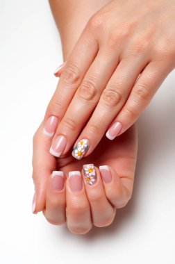 Fransız manikürü, beyaz arka planda uzun kare tırnaklı papatyalar. Yanmış eller.