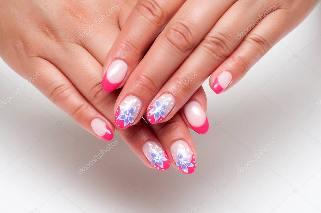Coral French manicure with painted blue flowers and white dots on long oval nails close-up on a white background. Summer flower manicure.