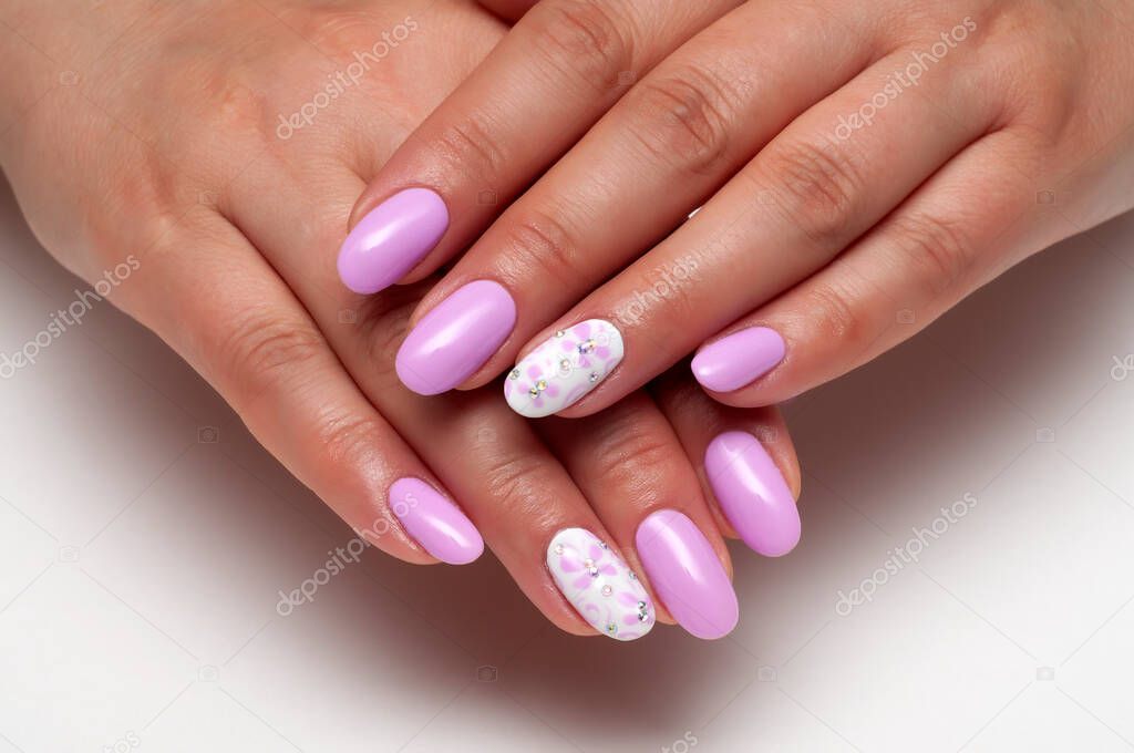 Lilac, white manicure with butterflies and crystals on long oval nails on a white background close-up.