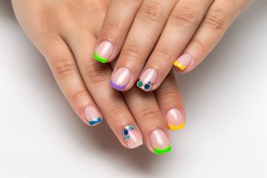 Çok renkli sarı, mavi, yeşil ve mor manikürlü. Kare uzunluğundaki tırnaklarında şekerleme var.