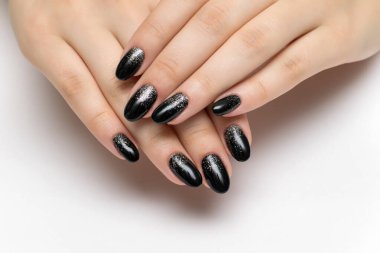 Beyaz arka planda uzun oval tırnaklı gümüş pullu şenlikli siyah manikür.