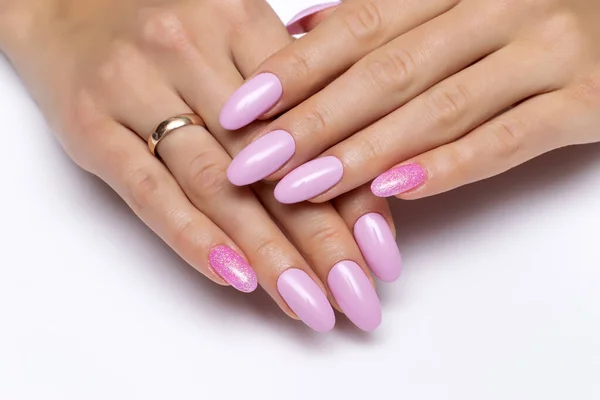 Gel. Pink manicure with pink sequins on long oval nails close-up on a white background.