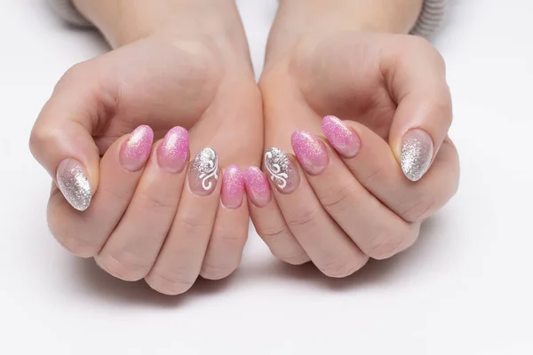 Gel nail design. Shiny pink, silver manicure with white lace, monograms, abstraction on short oval nails close-up on a white background