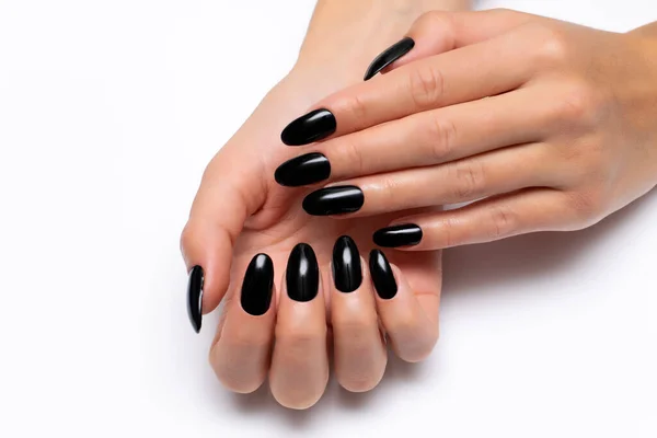 Gel black manicure on long oval nails close-up on a white background.