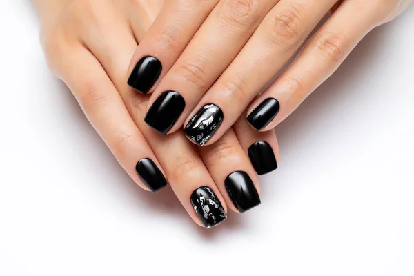 Design of nails for Halloween. Black manicure with a silver nail on short square nails close-up on a white background. Gel manicure.