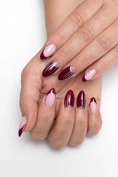 Burgundy French manicure with silver drawings, stripes on long sharp nails close-up on a white background