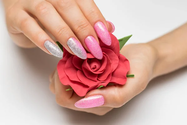 用尖尖的长指甲在手掌上涂上红玫瑰的新指甲 凝胶修指甲 粉红银制法式指甲和水晶 图库图片