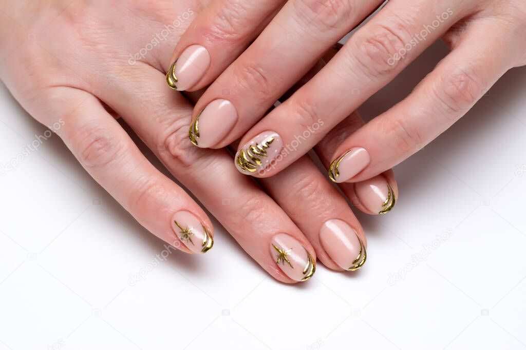 New Year's festive golden manicure with a painted tree and stars on short oval nails close-up on a white background. Gold casting.