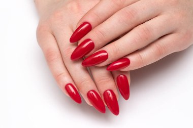 Klasik kırmızı tırnaklar. Beyaz arka planda uzun keskin tırnaklı kırmızı manikür. Çivi stilettoları. Jel tırnaklar.