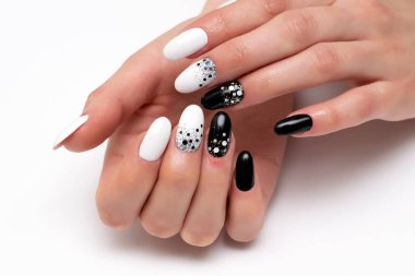 Siyah, beyaz manikür, büyük ve küçük noktalar, konfeti, beyaz arka planda uzun oval tırnaklar..