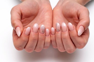 Düğün manikürü. Yüzüğünde kristaller ve çizgiler olan bir mezar. Kısa oval bacaklarda parmaklar. Beyaz arka planda yakın plan..