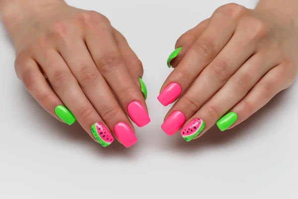 Summer pink and light green manicure with painted watermelons. Vacation manicure. Close-up on a white background. Acid colors of nails. Themed nails.