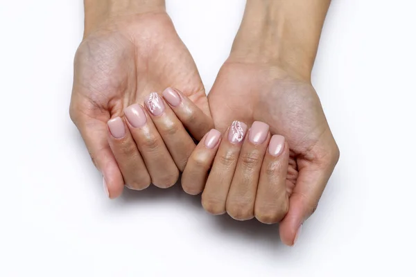 Close-up of pink manicure with a painted white feather on short square nails on a white background. Nude manicure. Beige, Body, Natural nails.