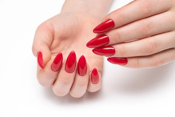Classic red nails. Red manicure on long sharp nails closeup on a white background. Shape nails stilettos. Gel nails.